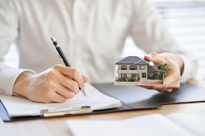 man writing holding a miniature house